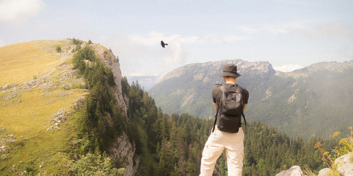 A traveler pausing to look out over a vast mountain landscape